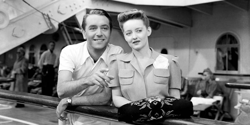 Paul Henreid and Bette Davis in 'Now, Voyager' looking at something in the distance, smiling