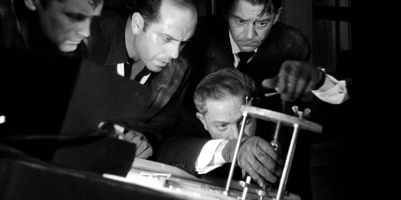Jean Servais, Carl Möhner, and Robert Manuel watching as Jules Dassin cracks a safe in Rififi