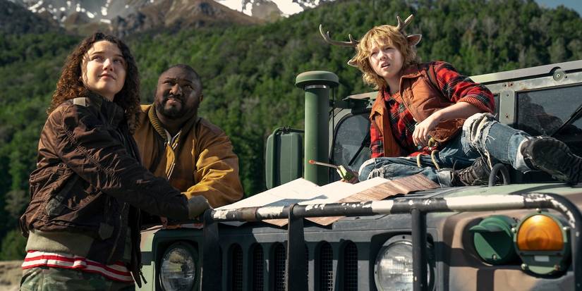 Stefania LaVie Owen, Nonso Anozie, and Christian Convery by a car outdoors looking away in Sweet Tooth.