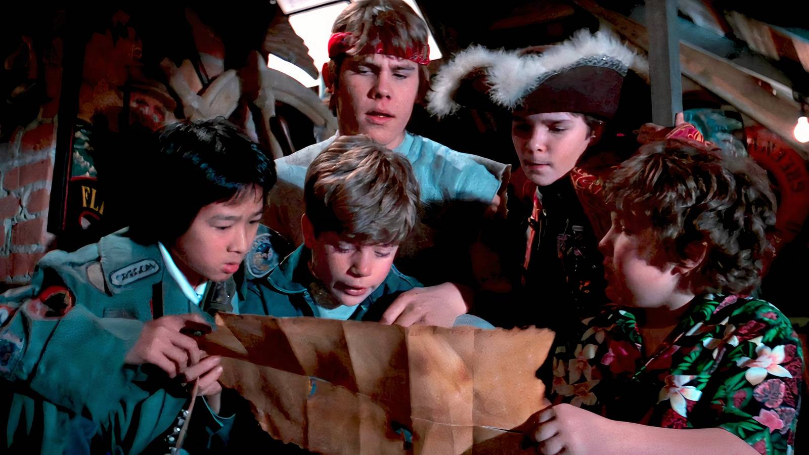 The Goonies surround a treasure map in the attic