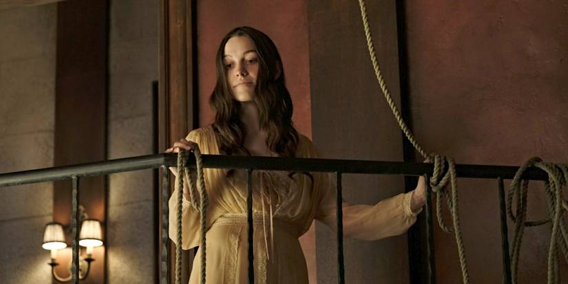 Victoria Pedretti as Nell in a night gown standing on a balcony next to a rope in The Haunting of Hill House.