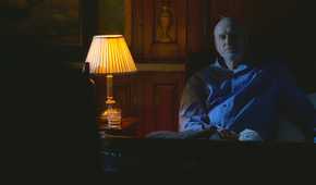 Charles Widmore (played by Alan Dale), sits up next to bed, where Benjamin Linus (Michael Emerson), has snuck in to threaten him in Lost’s Season 4 Episode ‘The Shape of Things to Come.’