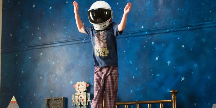 Auggie (Jacob Tremblay) jumps on the bed while wearing his astronaut helmet