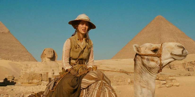 Adele (Louise Bourgon) rides a camel with the Sphinx and Pyramids of Giza in the background