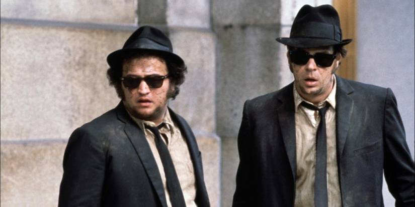 The Blues Brothers look shocked and disheveled on the street outside in The Blues Brothers.