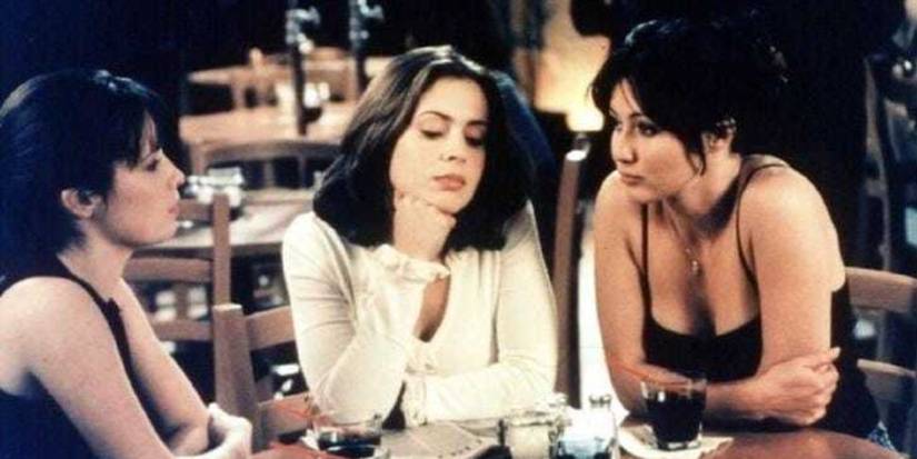 Shannen Doherty, Alyssa Milano, and Holly Marie Combs sitting at a restaurant in Charmed