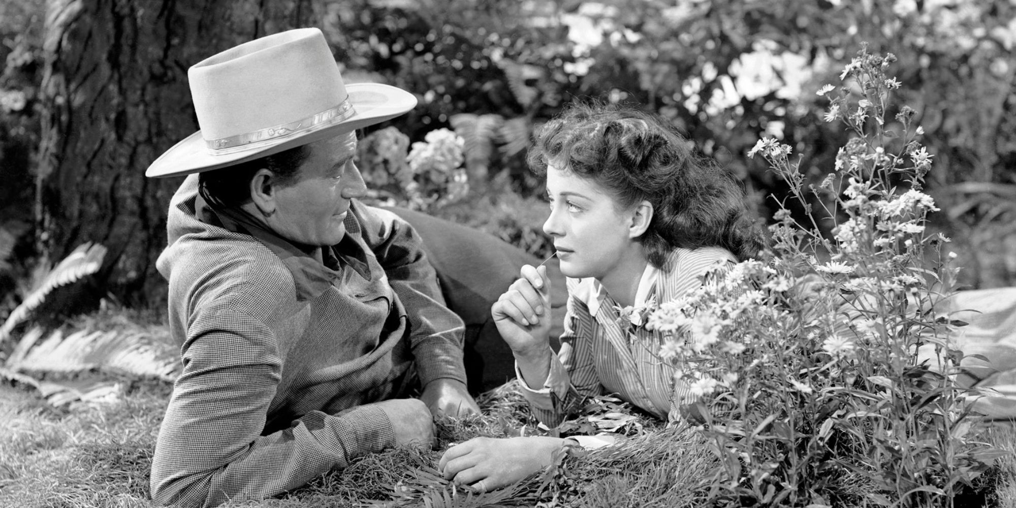 John Wayne and Gail Russell lying in the grass together and looking at each other in Angel and the Badman