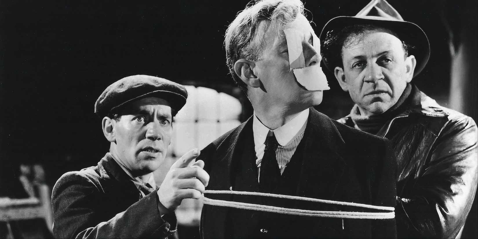 Two men looking at something off camera and another man tied up in The Lavender Hill Mob