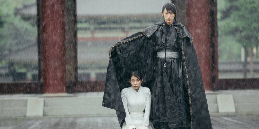 Lee Joon-gi uses his cloak to shield IU from the rain as she kneels in Moon Lovers Scarlet Heart Ryeo.