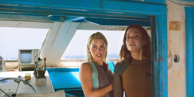 Kate and Lisa stand in wetsuits looking through the doorway from the bridge of the diving ship