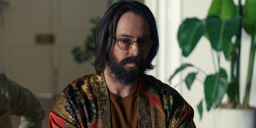 Martin Starr, Bodhi olarak desenli bir gömlek giydi, başını hafifçe aşağı eğerek, Tulsa King Sezon 1, Bölüm 9'da.