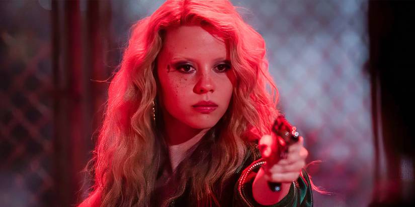 Mia Goth holding a gun under neon lighting with blonde hair in MaXXXine.
