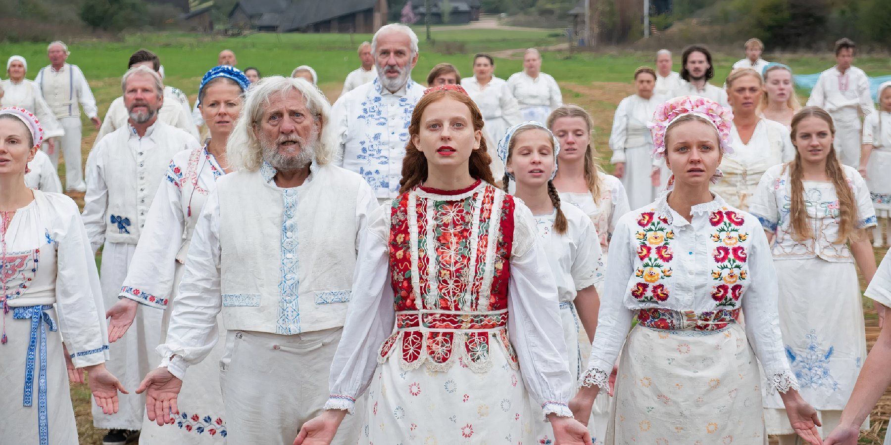 Pagan cult members hold their arms down and open during a ritual in Midsommar