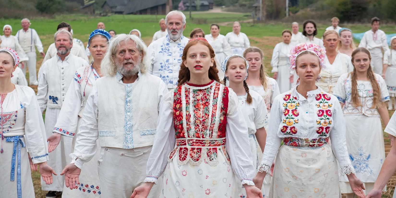 Pagan cult members hold their arms down and open during a ritual in Midsommar