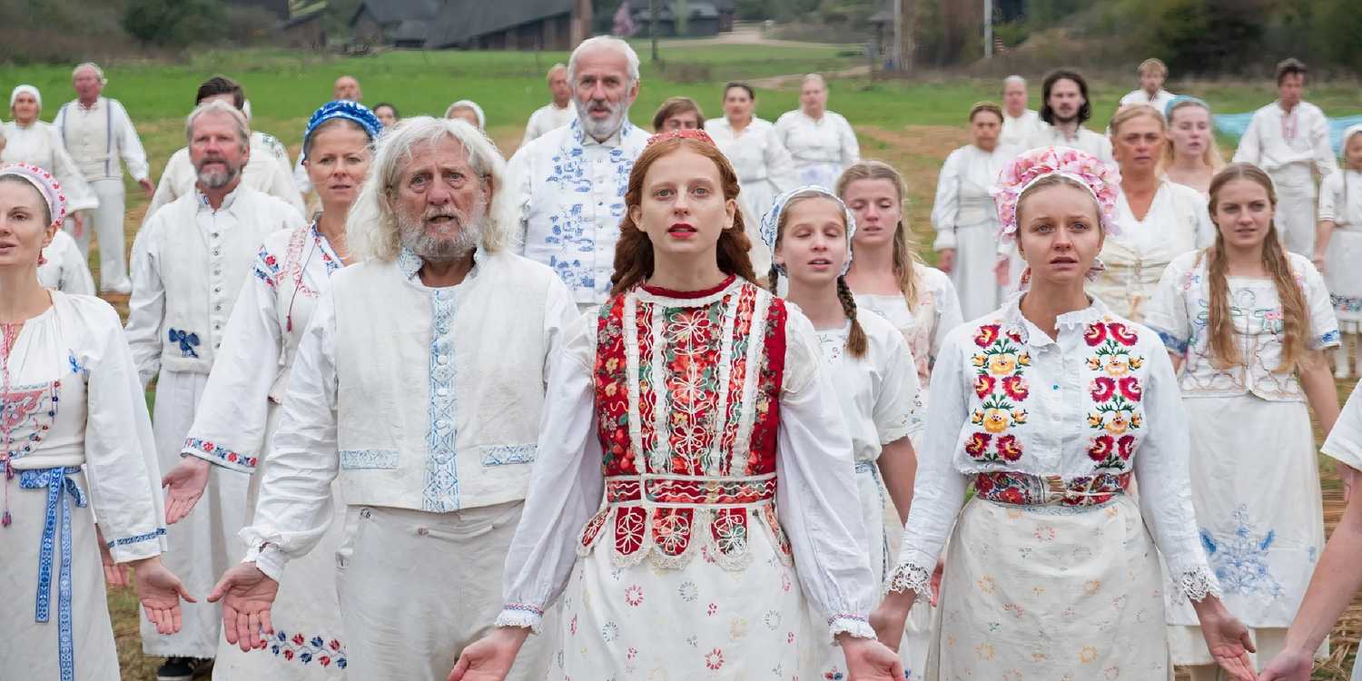 Pagan cult members hold their arms down and open during a ritual in Midsommar