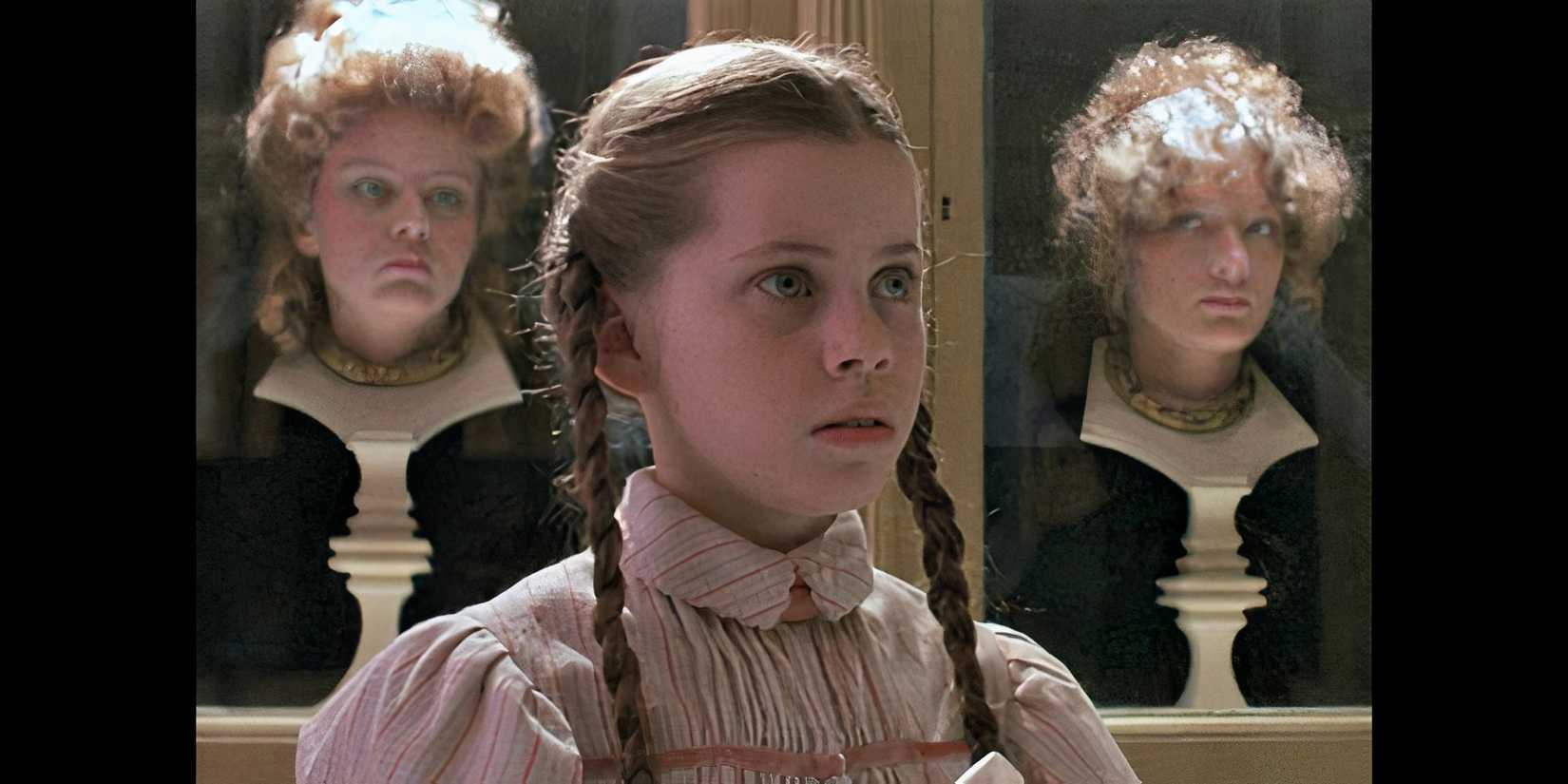 A young girl in braids with two women as statues behind her in Return to Oz.