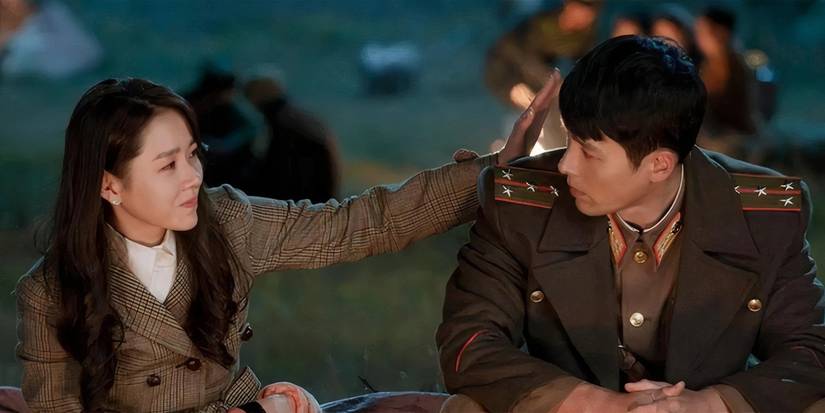 Se-ri patting Jeong-hyeok on the back near a campfire in Crash Landing on You.