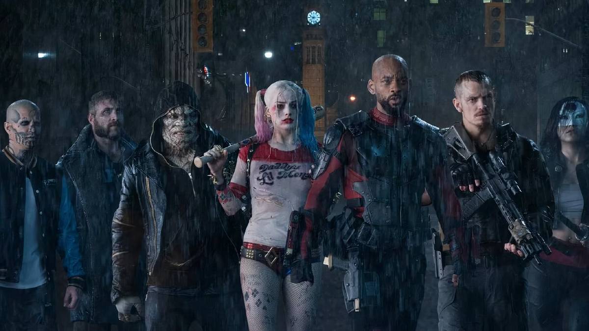 The Suicide Squad stands in a line in the rain, armed and ready to fight.