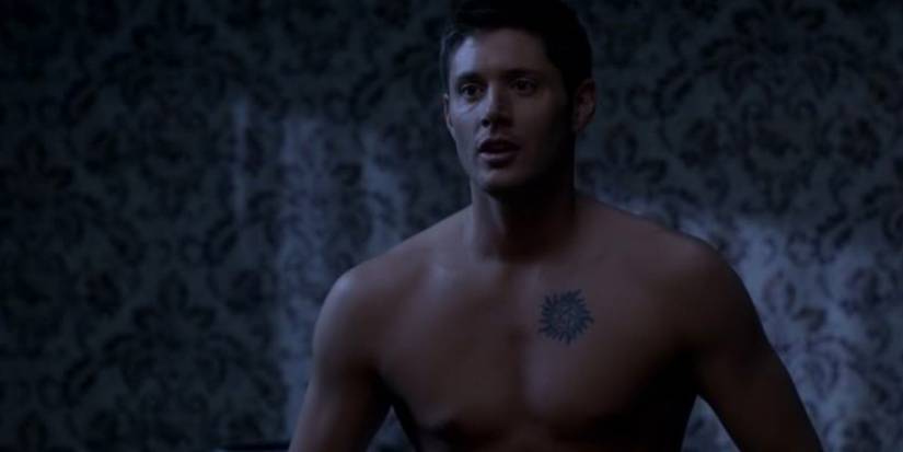 Jensen Ackles as Dean Winchester with his shirt off and a protection tattoo on his chest