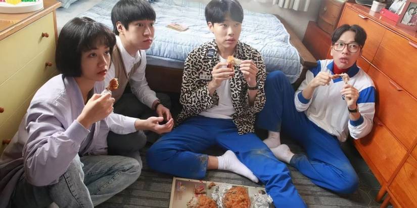 The cast of 1988 eating chicken on a bedroom floor in Reply 1988.