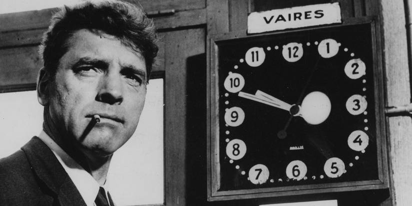 Burt Lancaster as Paul Labiche standing next to a clock in The Train (1964)