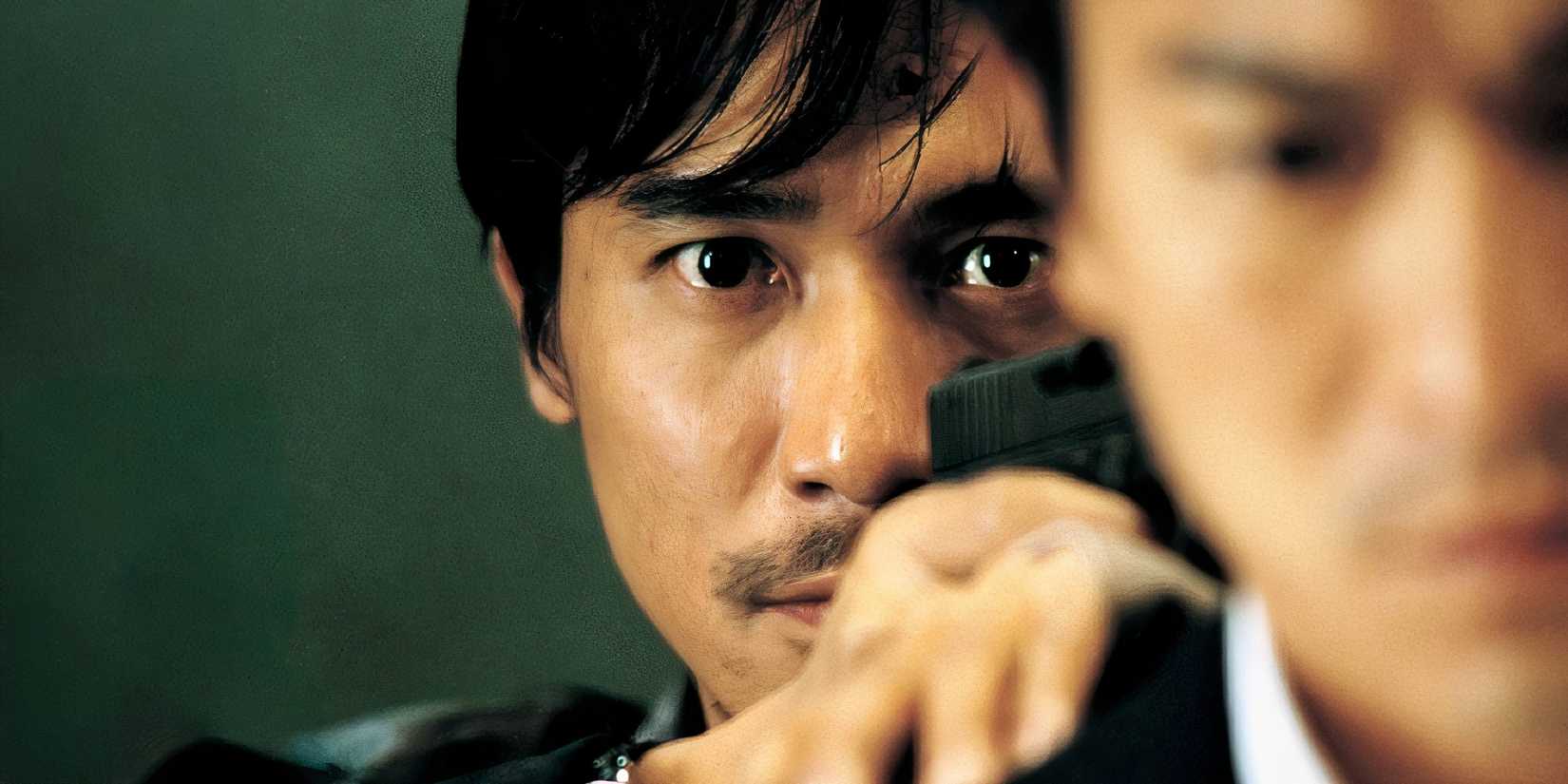 Tony Leung Chiu-wai as Chan Wing Yan in Infernal Affairs hiding behind a man.