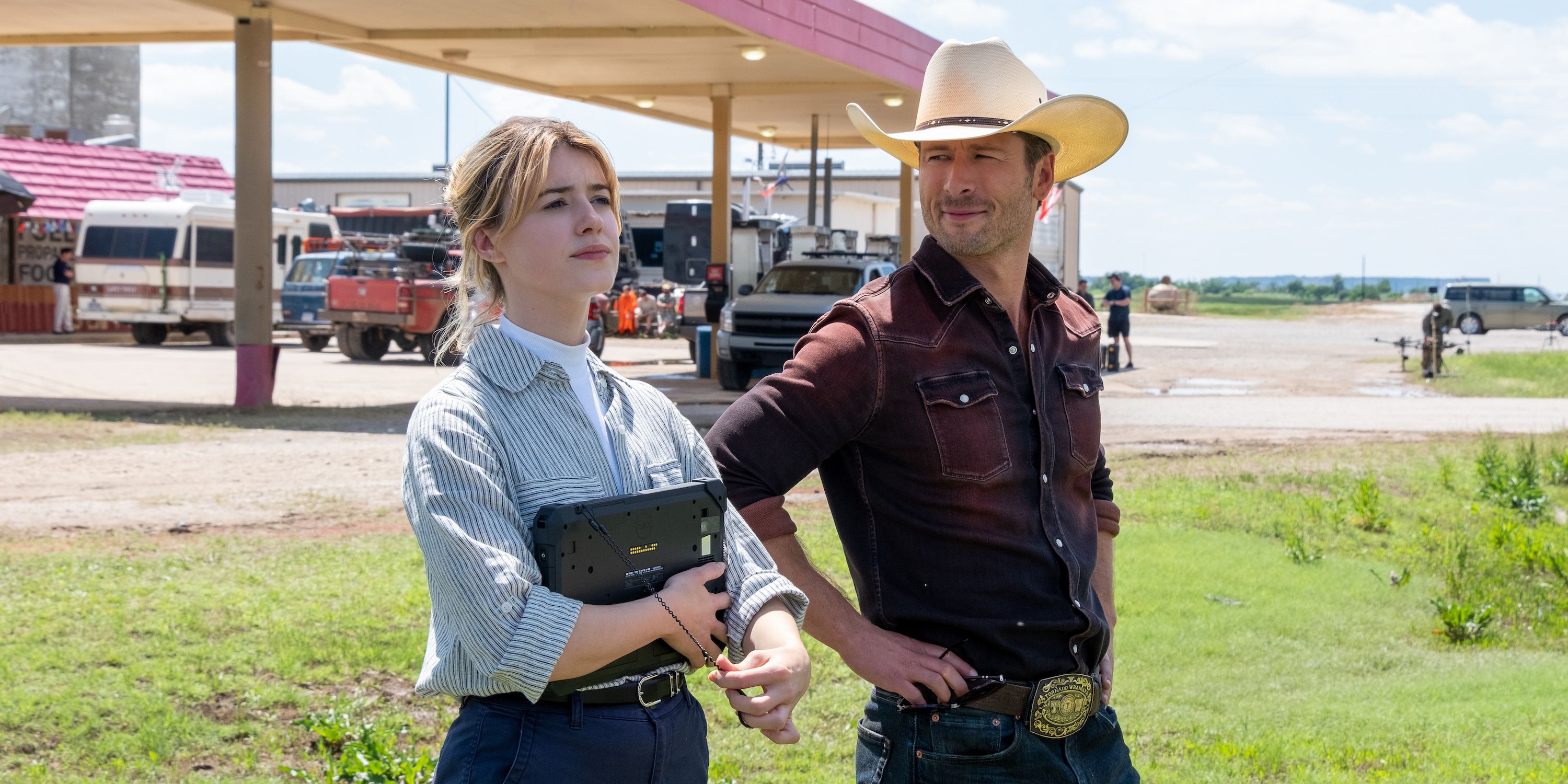 Tyler Owens (Glen Powell) and Kate Carter (Daisy Edgar-Jones) stand together outside in Twisters.