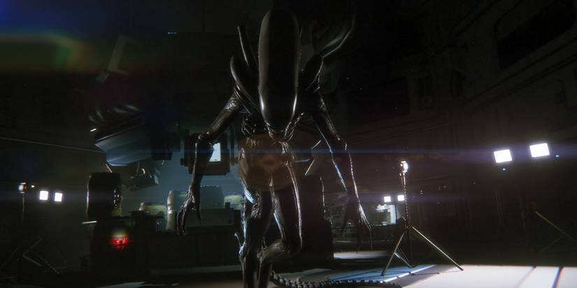 A low to the ground first-perspective shot of a xenomorph standing in a semi-crouch and facing the camera with its teeth bared in the Alien: Isolation video game
