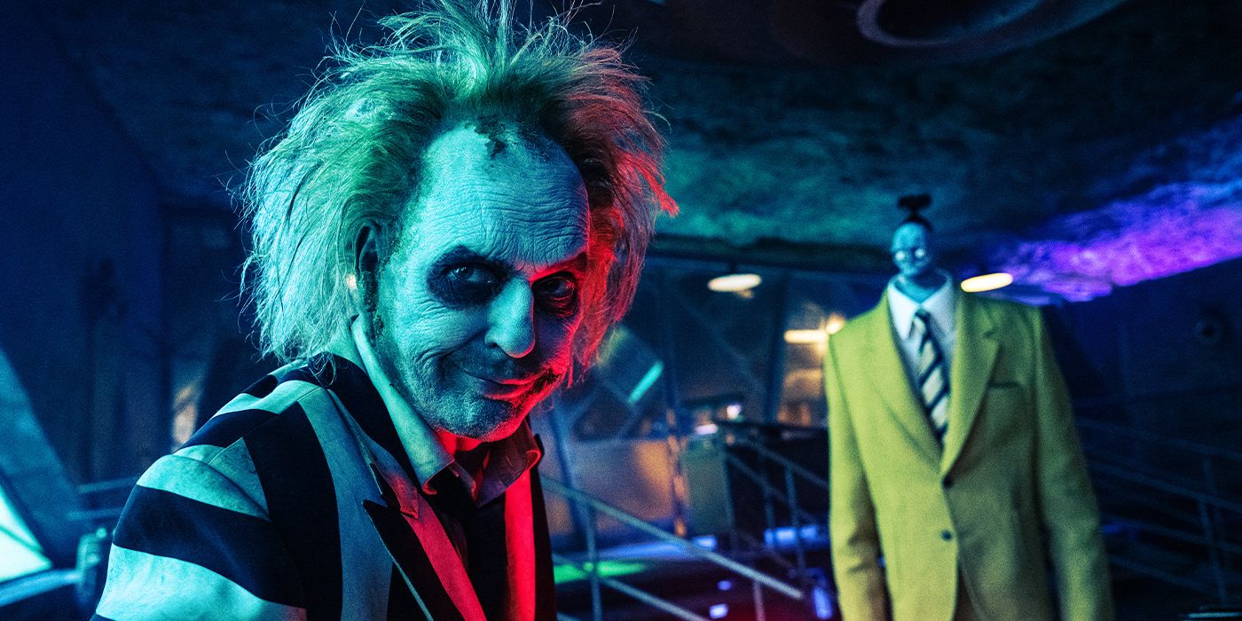Michael Keaton as Beetlejuice turned towards the camera smirking with Bob in the background