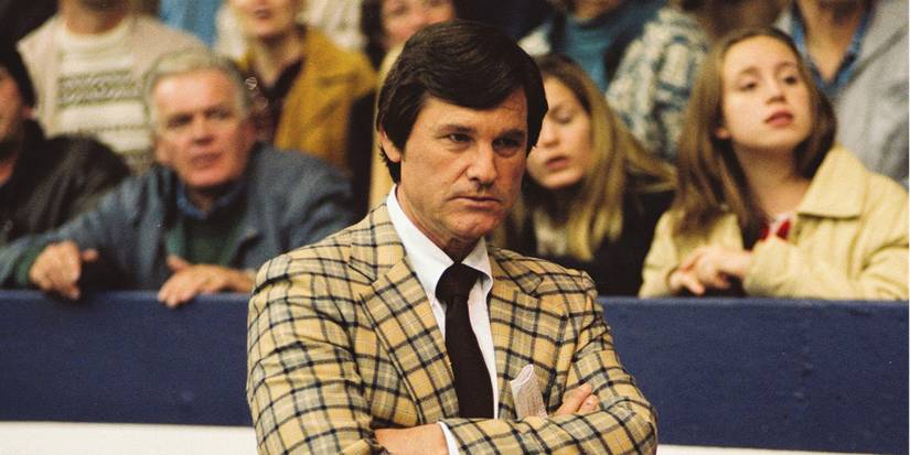 Kurt Russell as Herb Brooks with his arms folded at a hockey game in Miracle