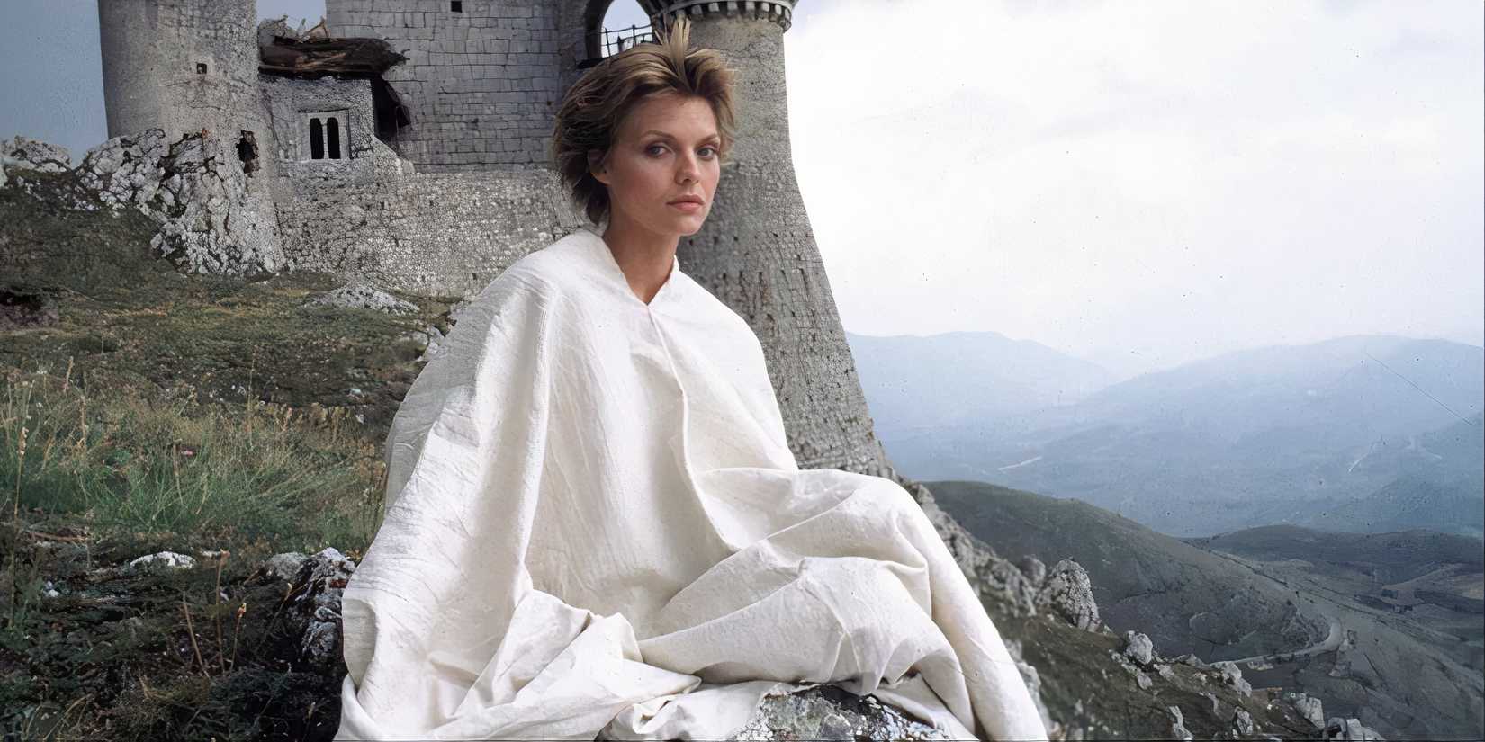Iseabeu of Anjou sitting on the grass with a castle in the background in Ladyhawke