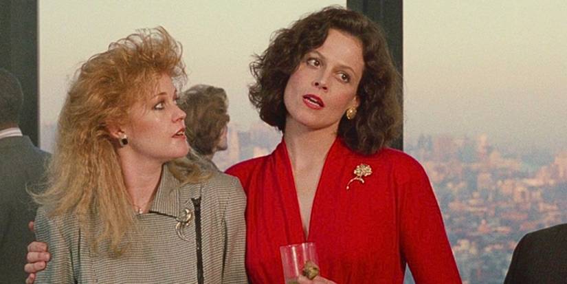 Melanie Griffith looks at Sigourney Weaver with surprise as she is embraced by Weaver, her duplicitous boss, in Working Girl.