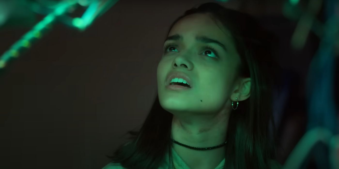 Rachel Zegler nervously looking up at something offscreen with a green glow.