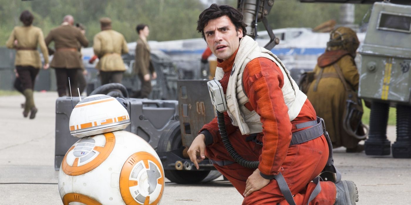 Oscar Isaac as Poe Dameron kneeling with BB-8 in Star Wars: The Force Awakens