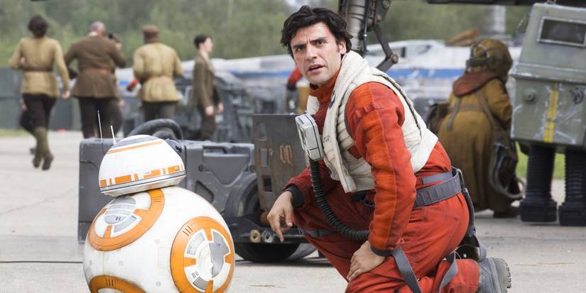 Oscar Isaac as Poe Dameron kneeling with BB-8 in Star Wars: The Force Awakens