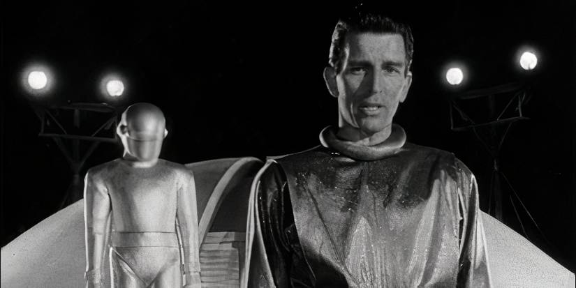 A man in a space suit stands in front of another figure and a flying saucer in The Day the Earth Stood Still.