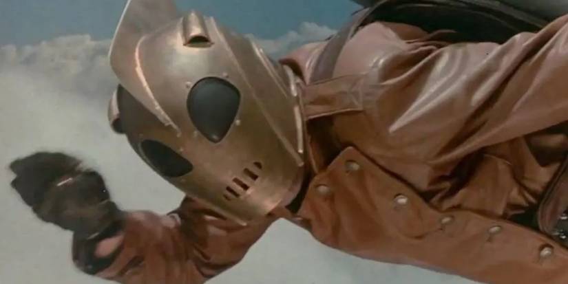 A masked superhero in a leather jacket flies through the sky in The Rocketeer.