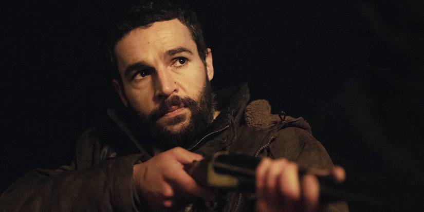 Christopher Abbott lifting up a rifle outside at night in Bring Them Down