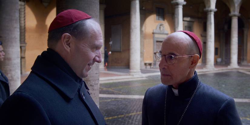 Ralph Fiennes  as Cardinal Thomas Lawrence and Stanley Tucci as Cardinal Aldo Bellini side by side talking in Conclave