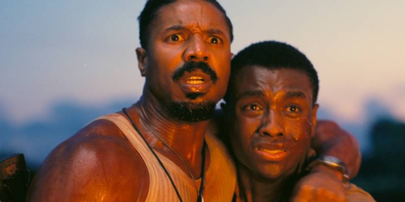 Michael B. Jordan and a young man looking ahead with emotional expressions in Sinners.