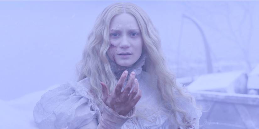 Edith in a snowstorm holding out a bloodied hand in Crimson Peak