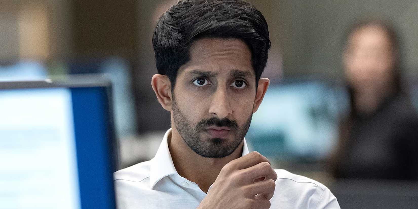 Rishi Ramdani (Sagar Radia) sitting at his desk in Industry.