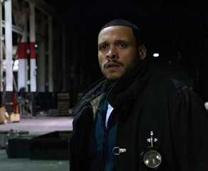 Joe Minoso as Joe Cruz in bunker gear stands in the middle of an abandoned building in Chicago Fire.