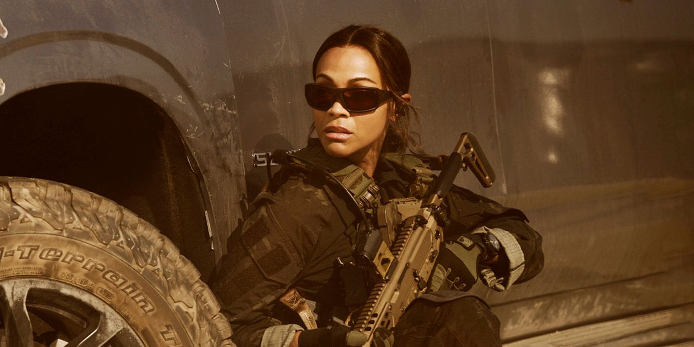 Zoe Saldana as Joe in military gear and sunglasses behind the wheel well of a truck in Lioness Season 2.