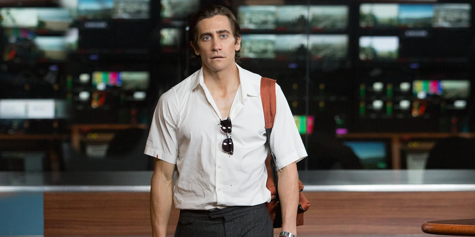 Jake Gyllenhaal stares blankly ahead in front of TV screens in Nightcrawler (2014)