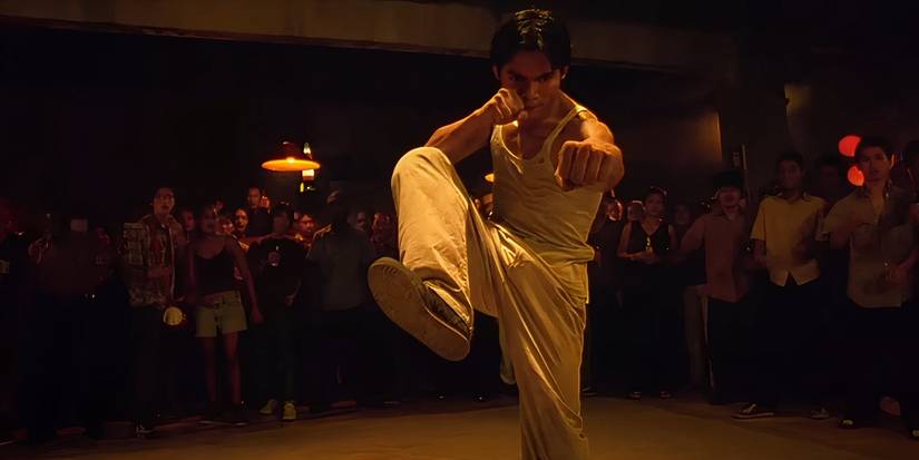 Tony Jaa with a raised knee in a martial arts stance in 'Ong-Bak'.