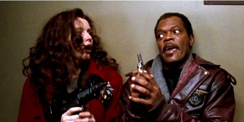 Geena Davis and Samuel L Jackson as Samantha and Hitch holding guns standing in a hallway in 'The Long Kiss Goodnight'