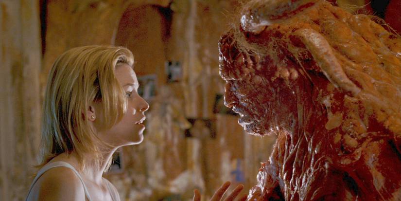 Starla in profile staring back at Grant Grant in full alien form in Slither.