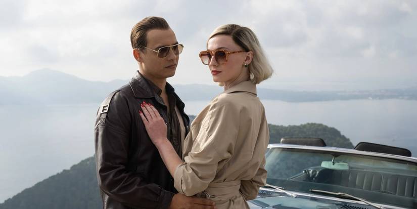 Frank Dillon standing in front of Sophie Turner with his hands on her hips next to a car in 'Joan'.