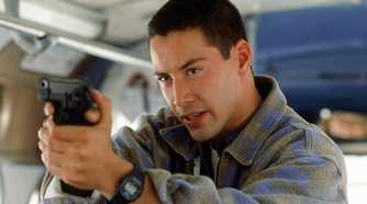 Keanu Reeves as Jack pointing a gun on a bus in Speed.